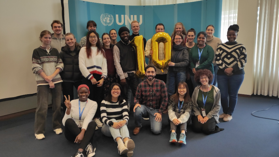 Master's programme students with a gold "10" balloon