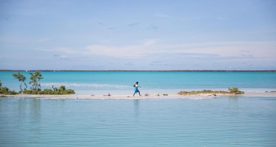 A child walking along a narrow piece of land between two bodies of water