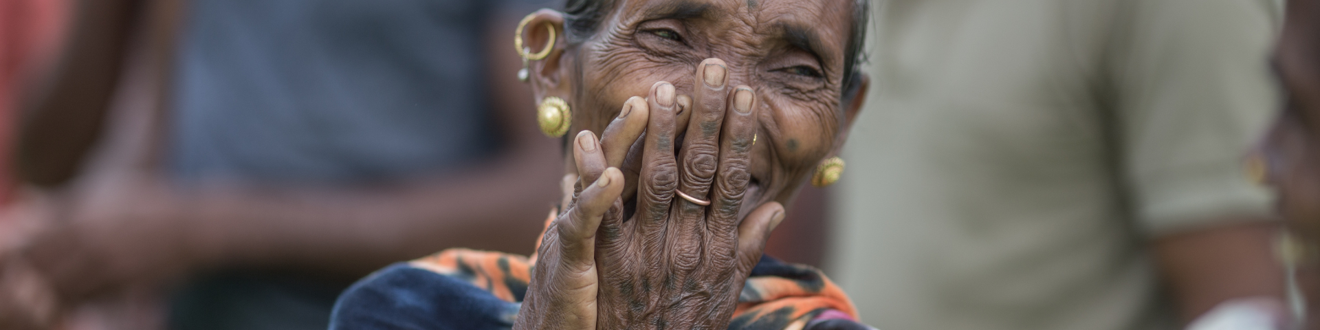 An overjoyed old woman smiling while covering her mouth with her hands
