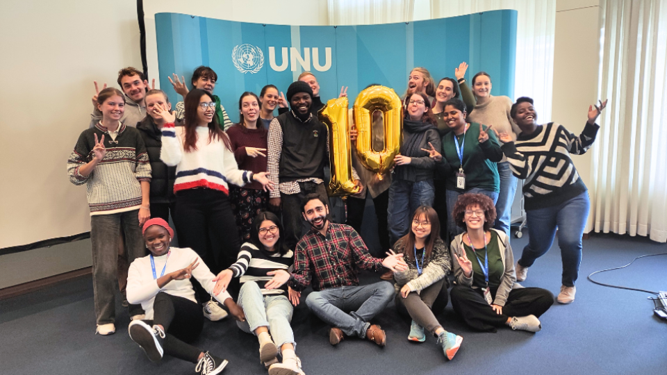 UNU-EHS Master's Programme students in front of UNU backdrop with balloons spelling out "10"